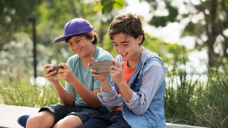 Zwei Jungen sitzen nebeneinander und spielen Spiele-Apps auf ihren Handys