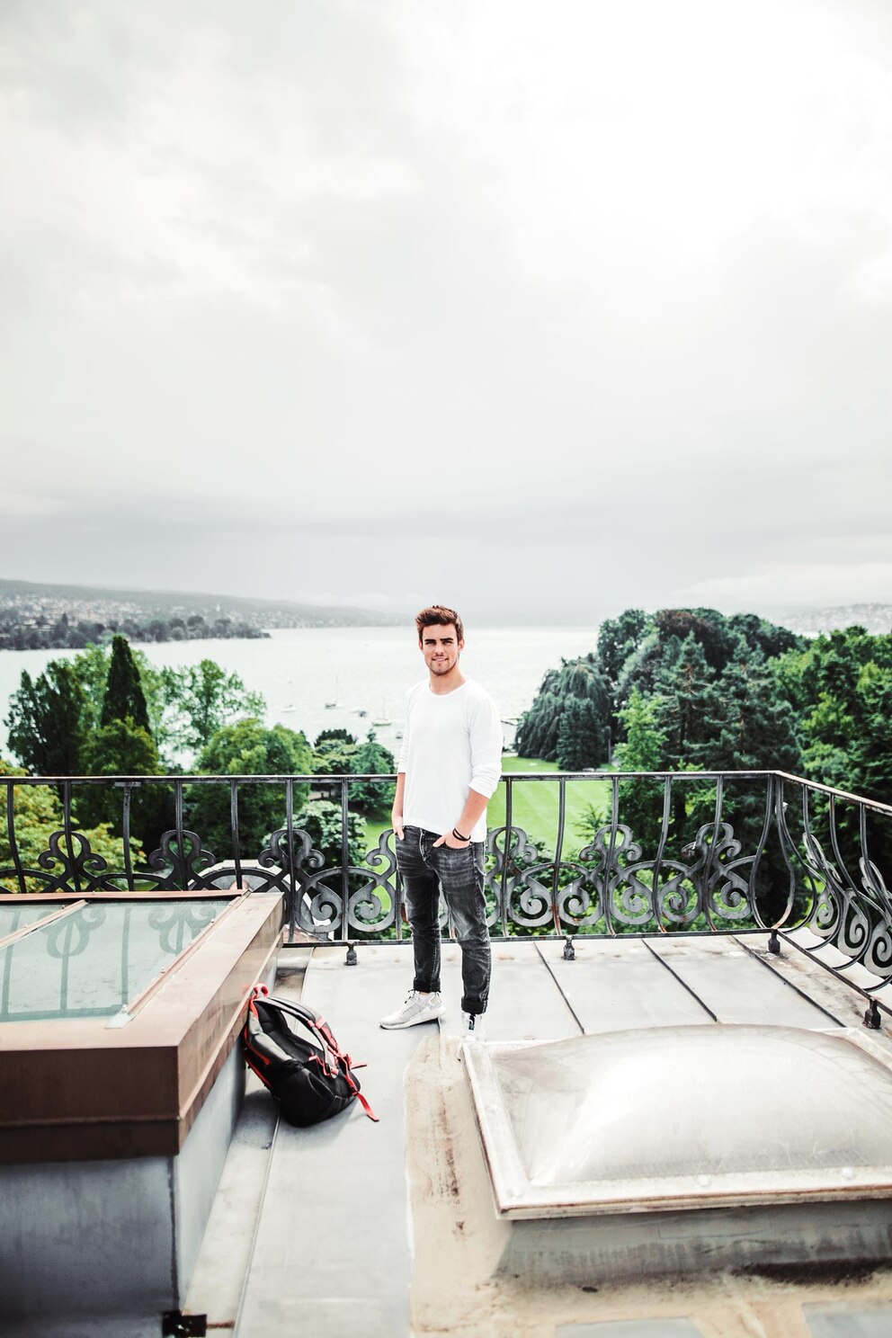 Rubin Lind steht auf einer Dachterrasse, vor ihm liegt sein Schulrucksack