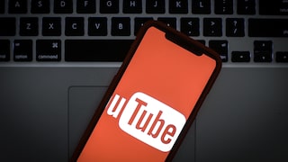 Das Logo von Youtube auf dem Display eines Smartphones vor einer Laptop-Tastatur