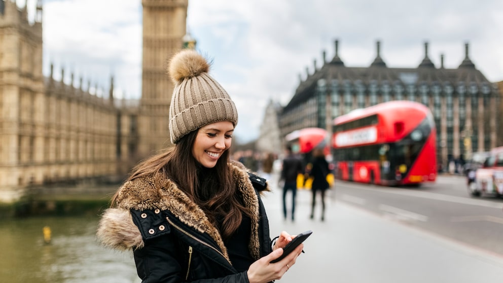 Frau mit Smartphone in London vor dem Big Ben