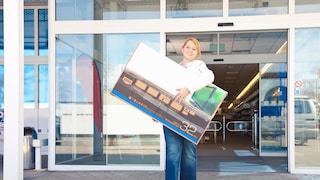 Frau trägt Fernseher aus Elektronik-Markt