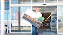 Frau trägt Fernseher aus Elektronik-Markt