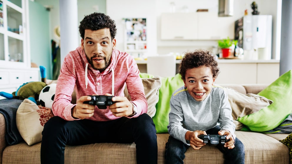 Vater und Sohn spielen mit Spielekonsolen