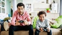 Vater und Sohn spielen mit Spielekonsolen