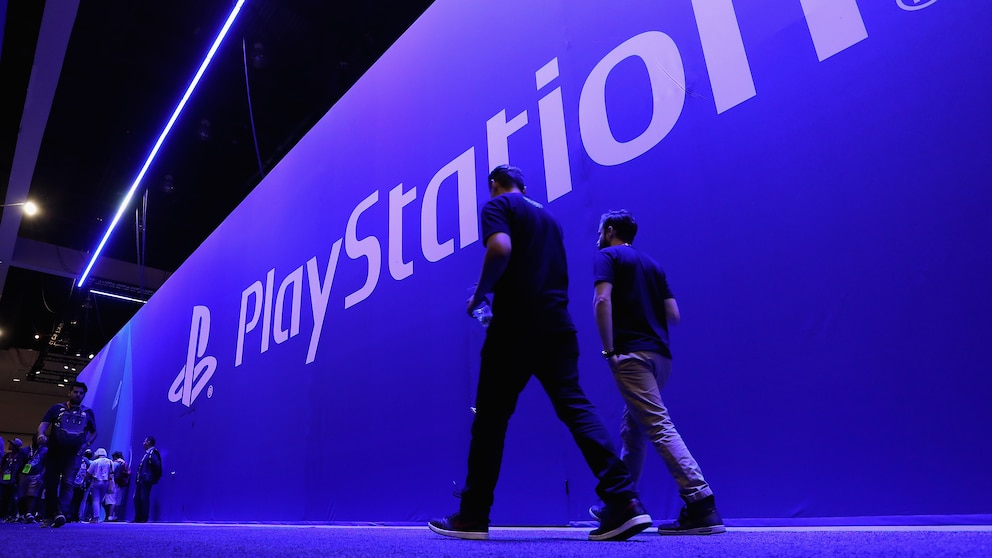 Menschen laufen vor einer großen Wand, auf der Playstation steht