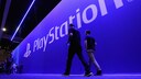 Menschen laufen vor einer großen Wand, auf der Playstation steht