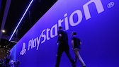 Menschen laufen vor einer großen Wand, auf der Playstation steht