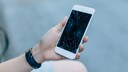 Smartphone mit einem zersplitterten Display in der Hand eines Menschens