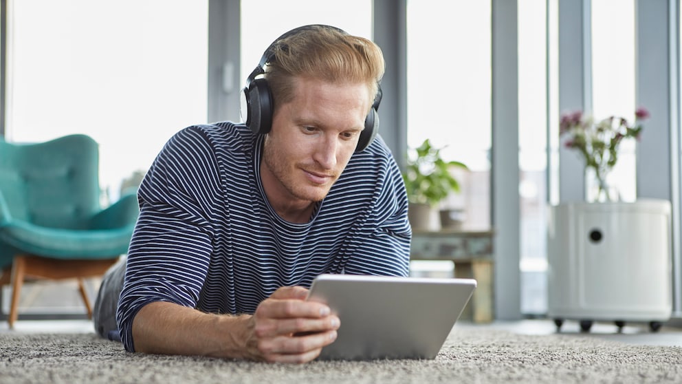 Amazon Prime Video Tipps Symbolbild: Junger Mann liegt mit Kopfhörern und Tablet auf dem Boden