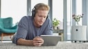 Amazon Prime Video Tipps Symbolbild: Junger Mann liegt mit Kopfhörern und Tablet auf dem Boden