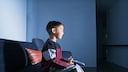 Netflix und Amazon Prime Video für Kinder Symbolbild: Ein kleiner Junge sitzt mit der Fernbedienung in der Hand auf dem Sofa