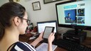 Amazon Kindle Oasis Test: Frau sitzt am Tisch und hält E-Book-Reader in der Hand