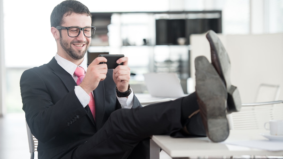 Symbolbild Smartphone Streaming App Quibi: Mann mit Handy im Büro