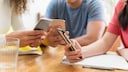 Drei junge Menschen mit Smartphone am Tisch
