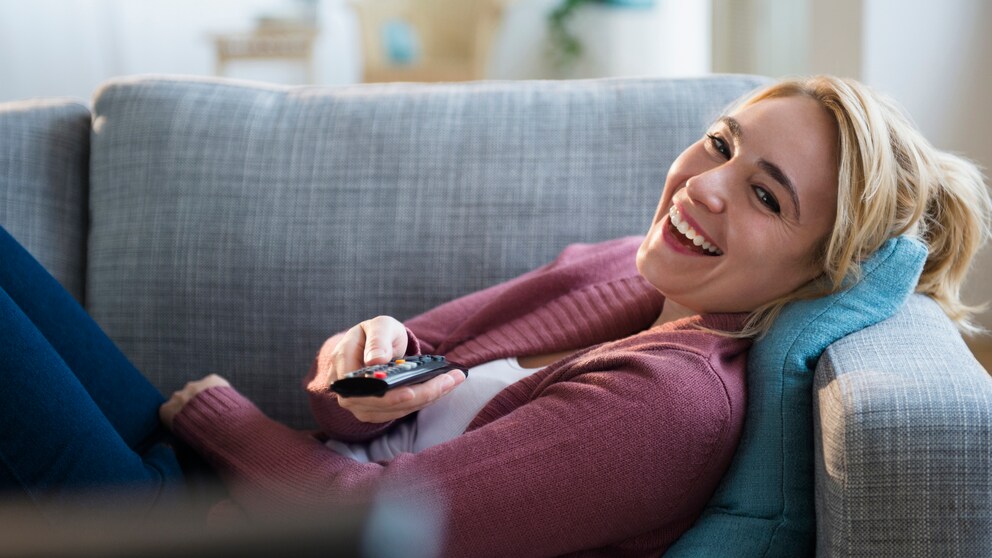 Frau auf dem Sofa schaut fern