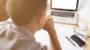 Mann an Schreibtisch mit Laptop