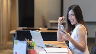 Frau sitzt vor dem Laptop und freut sich