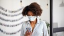 Frau mit Maske und Smartphone