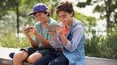 Giochi per cellulare: due ragazzi seduti uno accanto all'altro con i loro smartphone