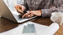 Online Banking TAN-Verfahren: Mann mit Handy und Bankkarte am Computer