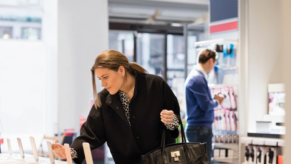 Frau betrachtet Smartphones im Handyshop