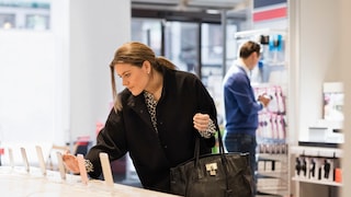 Frau betrachtet Smartphones im Handyshop