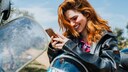 Frau mit Smartphone auf dem Motorrad