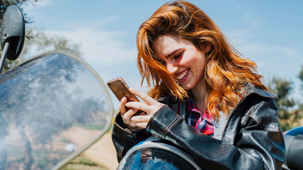 Frau mit Smartphone auf dem Motorrad