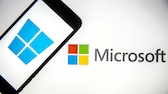 Smartphone mit Windows-Logo vor Microsoft-Logo