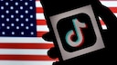 Smartphone mit TikTok-Logo vor US-Flagge