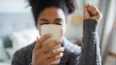 Frau mit Smartphone in Feier-Pose