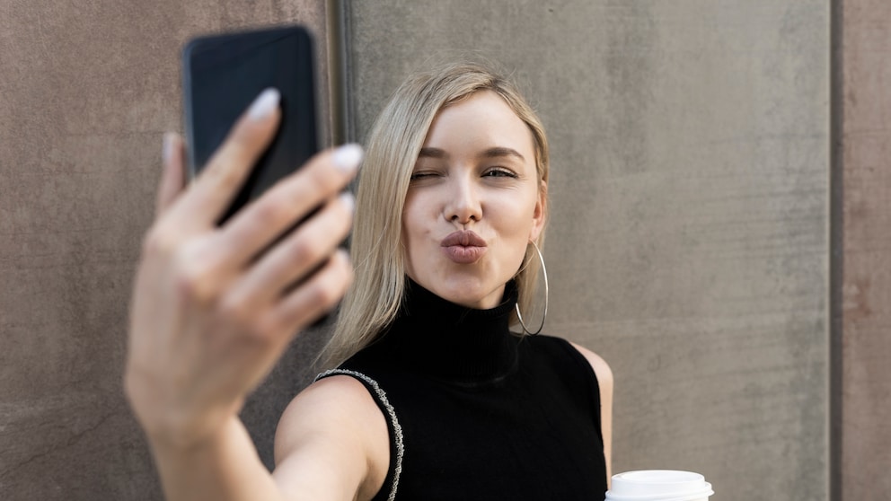 FolloInstagram-Follower: Junge Frau macht Selfie mit dem Smartphone und hat einen Kaffee in der Hand