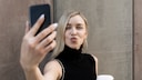 FolloInstagram-Follower: Junge Frau macht Selfie mit dem Smartphone und hat einen Kaffee in der Hand