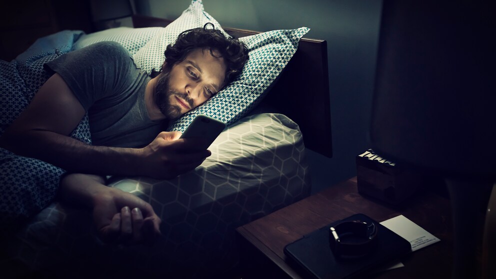 Mann im Bett mit Smartphone