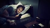 Mann im Bett mit Smartphone