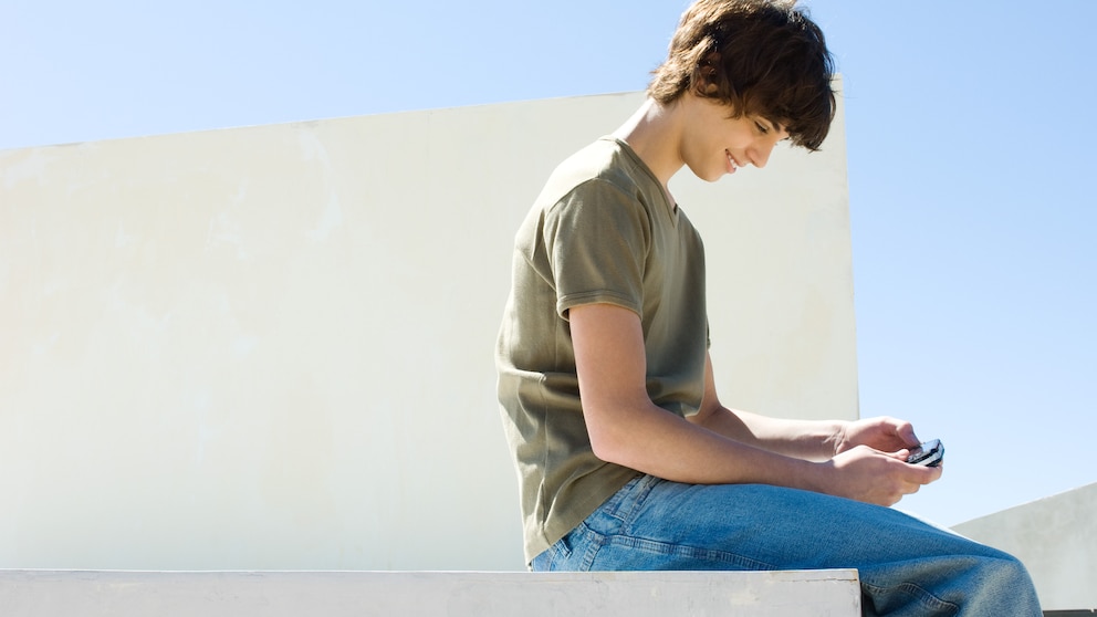 Microsoft xCloud Mobile Gaming: Junge mit Smartphone sitzt draußen