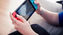 Nintendo Switch Reparatur Symbolbild: Frauenhände halten rot-blaue Nintendo Switch
