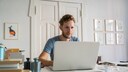 Symbolbild Gmail mit anderen Konten verknüpfen: Junger Mann am Laptop