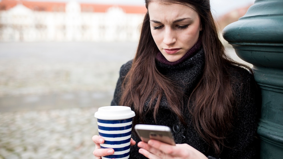 Frau schaut verärgert aufs Smartphone