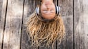 Musik-Streaming-Dienst: junge Frau liegt auf dem Boden und h&ouml;rt mit Kopfh&ouml;rern Musik