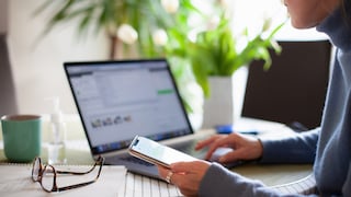 Frau mit Smartphone am Laptop