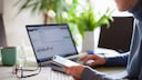 Frau mit Smartphone am Laptop