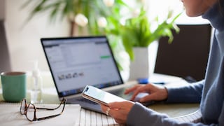 Frau mit Smartphone am Laptop