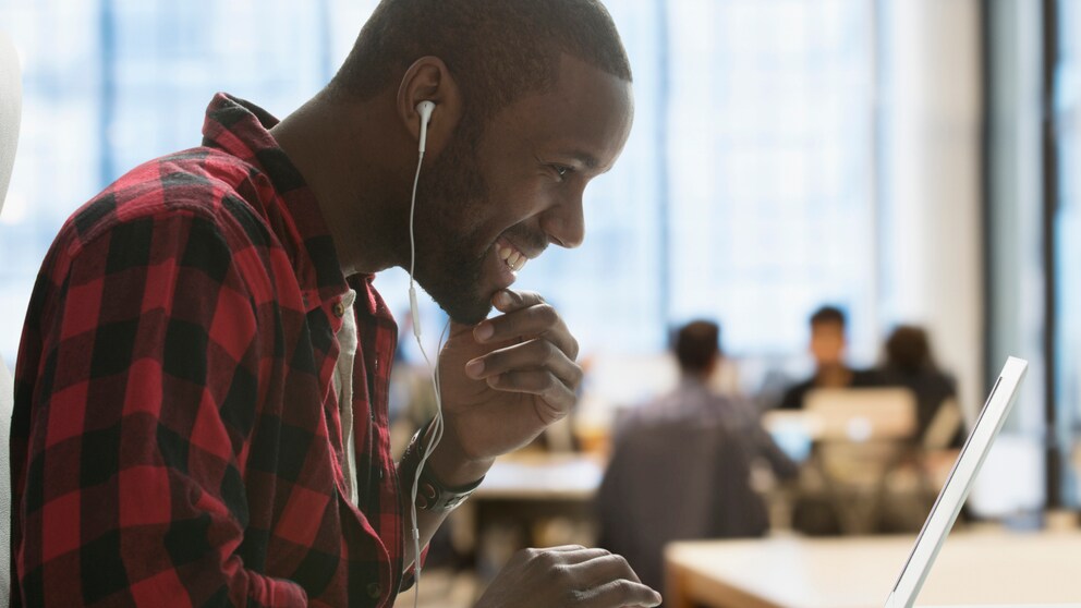WhatsApp Desktop Anrufe: Junger Mann mit Kopfhörern am Laptop