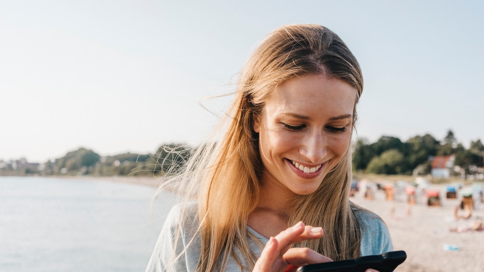 Frau mit Handy am Strand