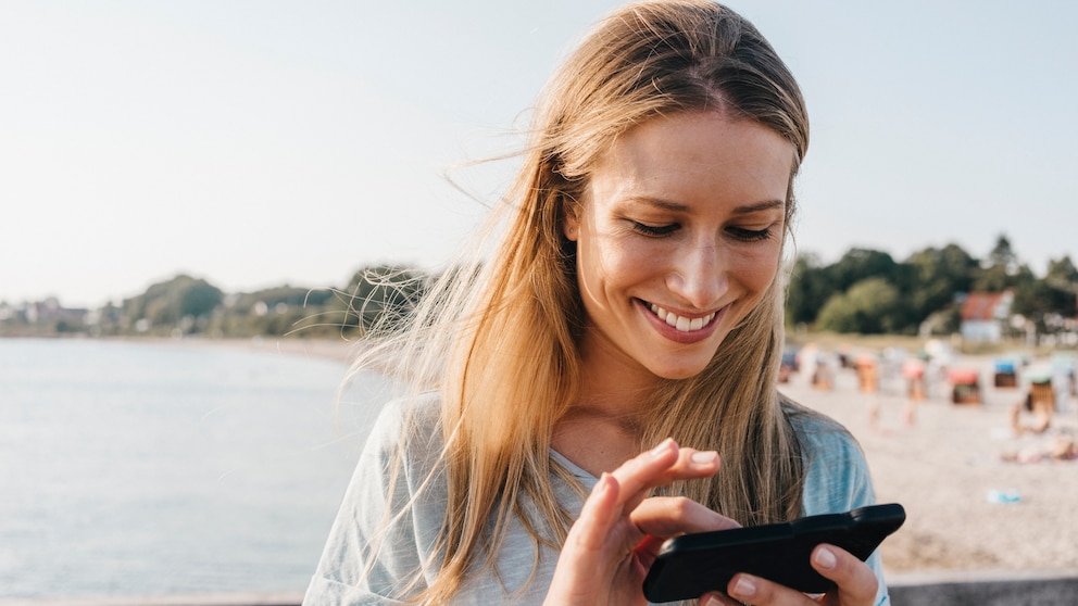 Frau mit Handy am Strand