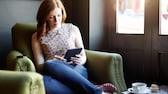 Frau mit E-Book-Reader auf einem Sessel