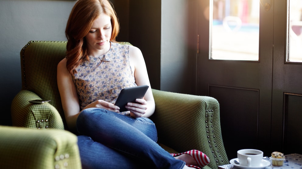 Frau mit E-Book-Reader auf einem Sessel