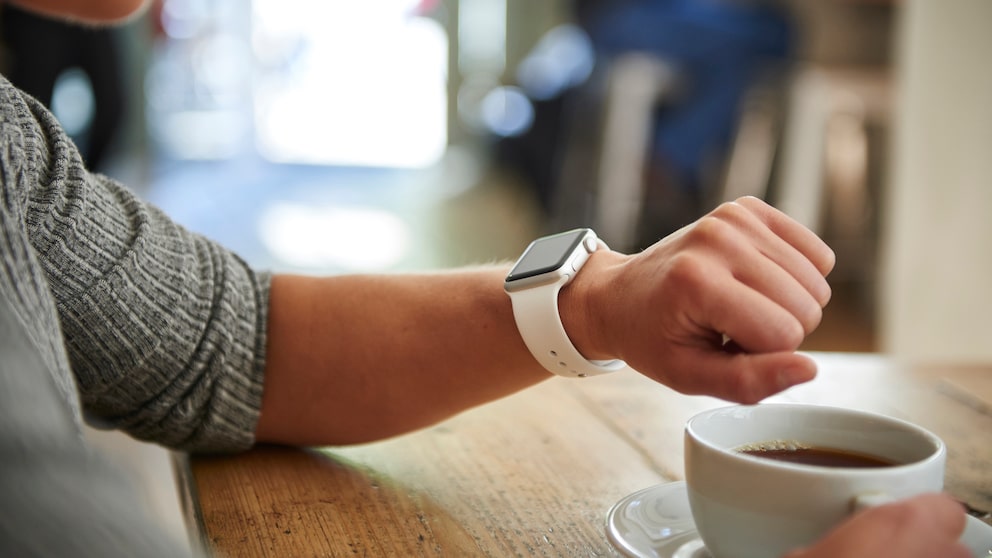 Apple Watch Apps: Apple Watch am Handgelenk neben einer Tasse Kaffee
