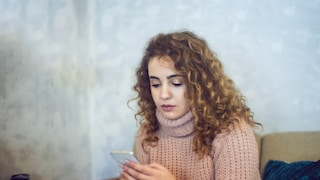 Frau schaut unglücklich aufs Smartphone